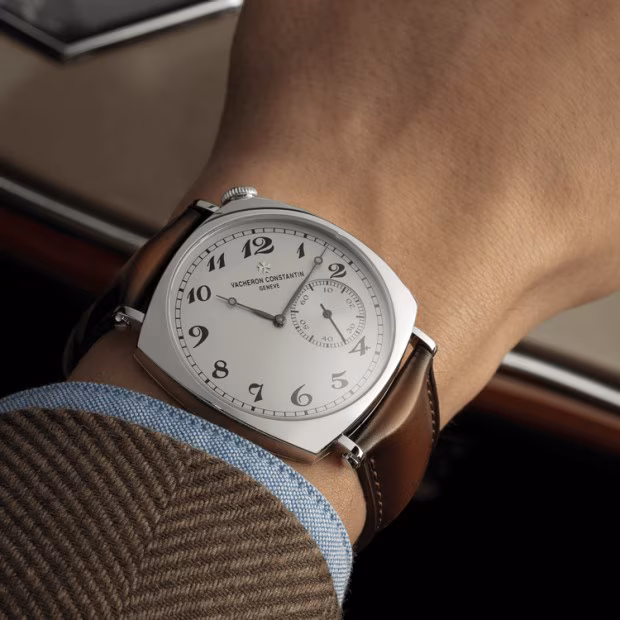 Vacheron Constantin American 1921 watch on wrist, featuring an off-centered dial and brown leather strap, exemplifying heritage and discreet elegance.